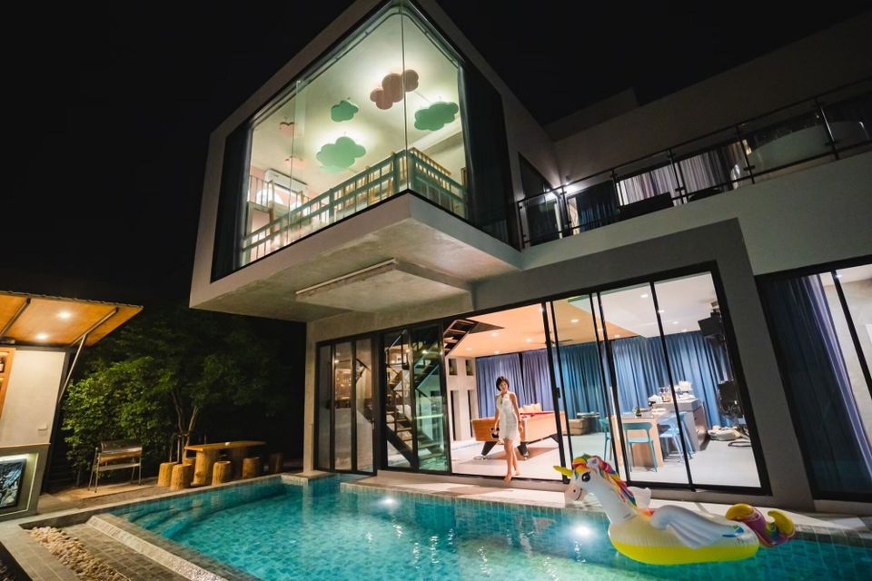 Holiday Sunset Villa IV in Hua Hin at night, featuring a lit pool with a unicorn float and modern exterior.