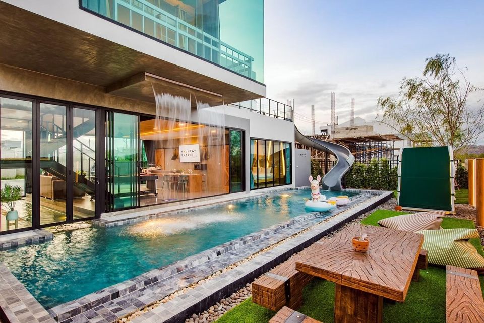 Holiday Sunset Villa IV in Hua Hin features a refreshing pool with a waterfall, a fun water slide, and a cozy outdoor dining area.