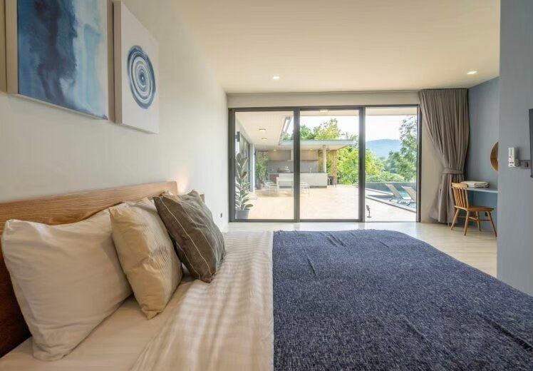 Spacious bedroom with a king-size bed, blue accents, and a private balcony overlooking the pool at Kin Khaoyai V Pool Villa.