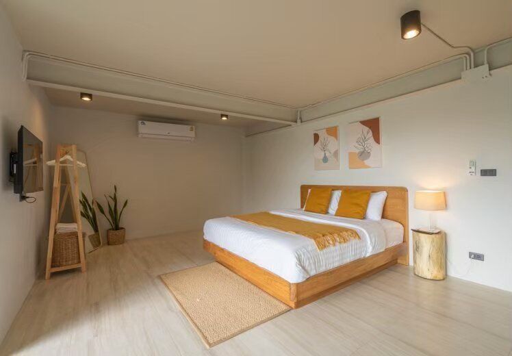 A minimalist king-size bed with yellow accents in a bedroom at Kin Khaoyai V Pool Villa, Khao Yai.