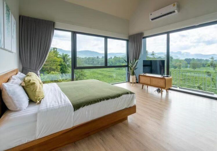 Spacious bedroom at Kin Khaoyai V Pool Villa with a comfortable bed, TV, and stunning mountain views from floor-to-ceiling windows.