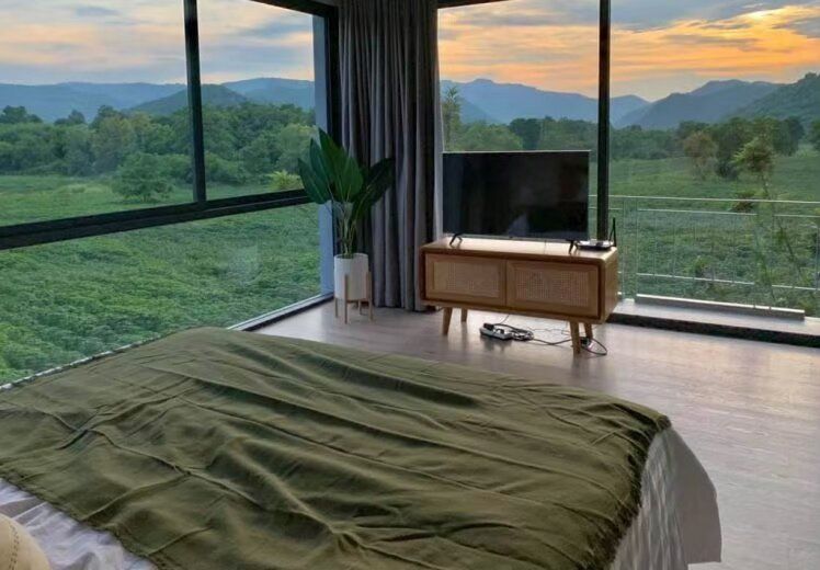 Bedroom with a king-size bed and large windows offering stunning mountain views at Kin Khaoyai V Pool Villa, Khao Yai.