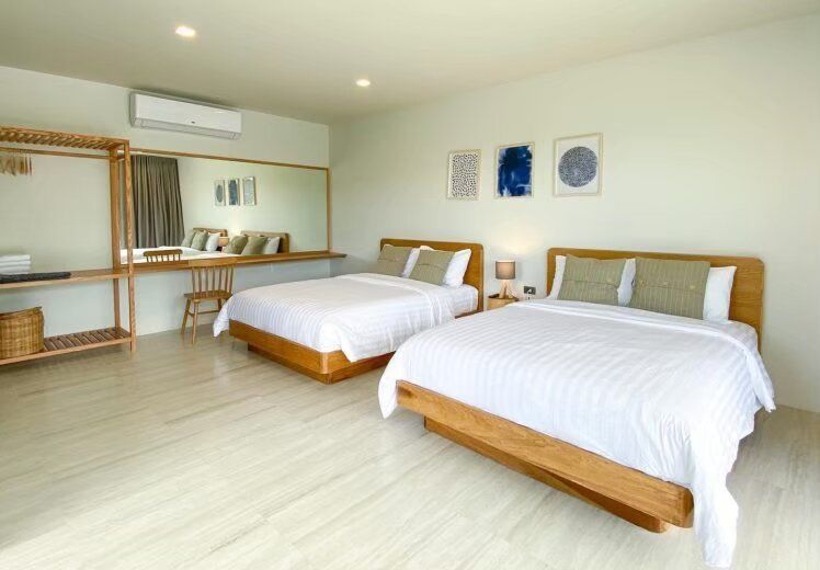 Bright bedroom at Kin Khaoyai V Pool Villa, Khao Yai, featuring two comfortable double beds with white linens and wooden frames.