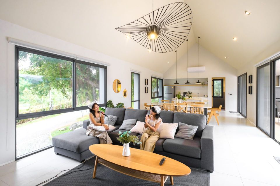 Living room karaoke setup at Kin Khaoyai V Pool Villa, หมูสี เขาใหญ่. Two women sing on the sofa.