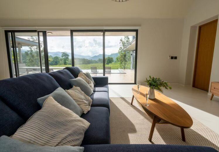 Spacious living room at Kin Khaoyai V Pool Villa, Khao Yai, with a comfortable blue sofa and stunning mountain views.