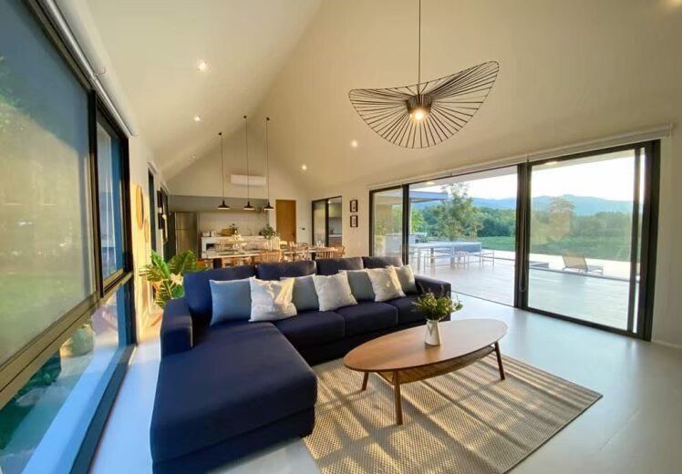 Spacious living room with a large L-shaped sofa and mountain views at Kin Khaoyai V Pool Villa, Khao Yai.