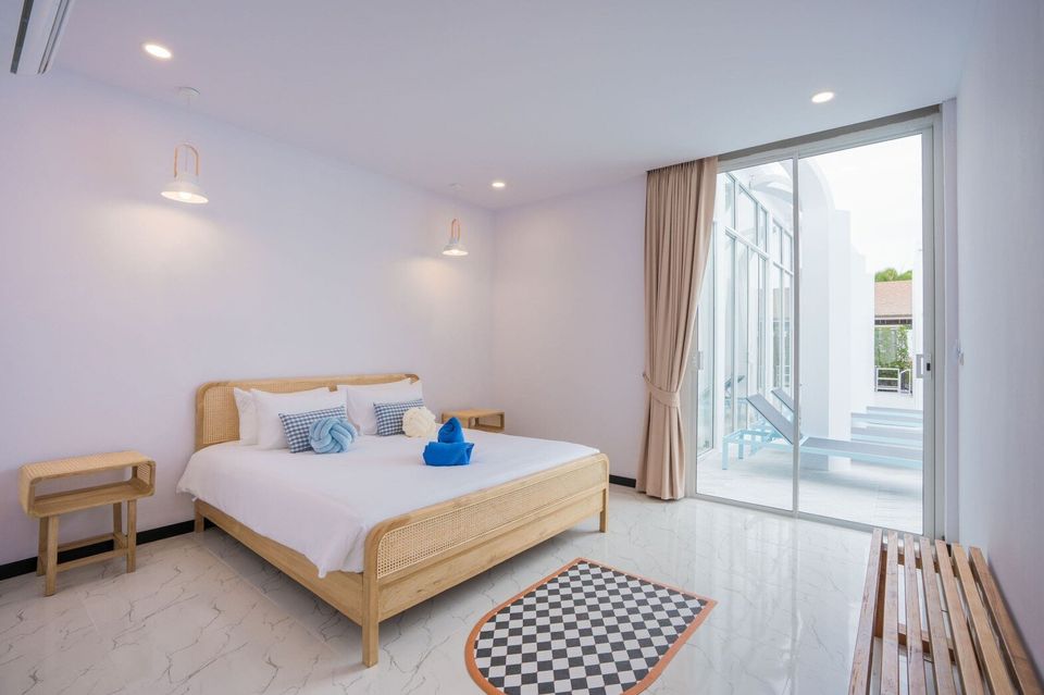 Bright bedroom at Miami Beach VI Pool Villa, Cha-Am, with a king-size rattan bed, white linens, and direct pool access.