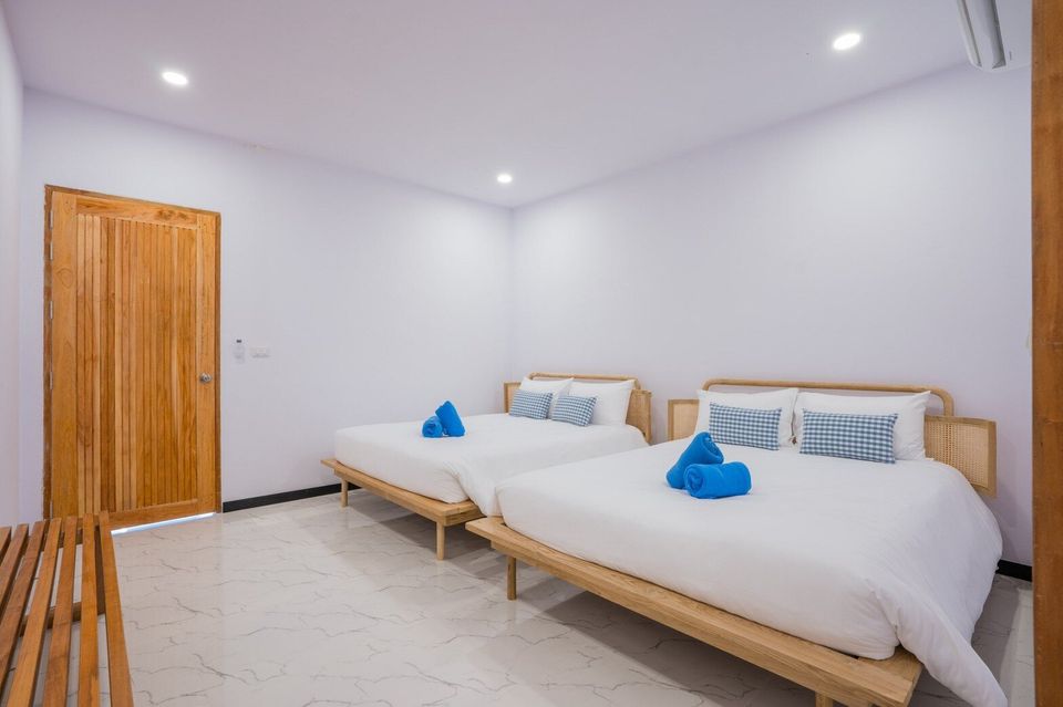 Bright bedroom at Miami Beach VI Pool Villa, Cha-Am, featuring two queen-sized beds with white linens and blue accents.