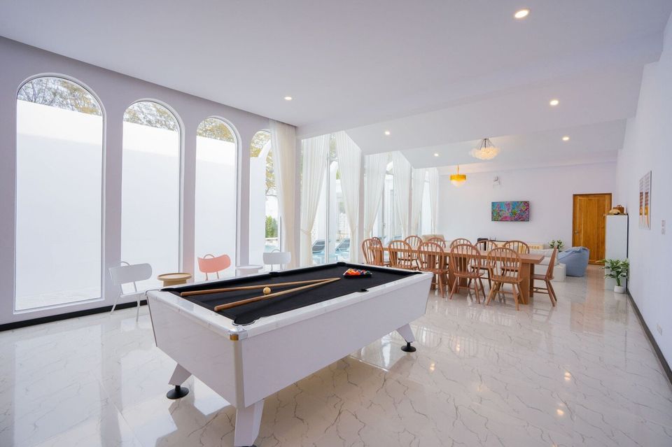 Spacious entertainment room with a white billiards table and a large wooden dining table at Miami Beach VI Pool Villa, Cha-Am.