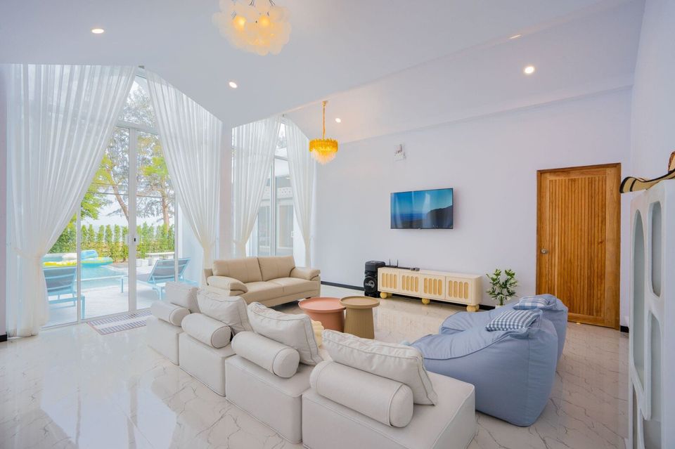 Spacious living room at Miami Beach VI Pool Villa, Cha-Am, with white sofas, TV, and large glass doors opening to the pool.