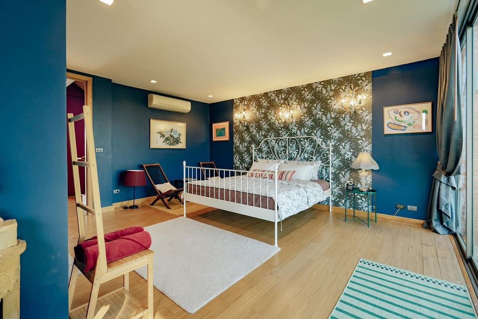 Bedroom at Pink Sand Beachfront Villa, บางละมุง พัทยาเหนือ. White metal bed frame, floral wallpaper, and blue walls.