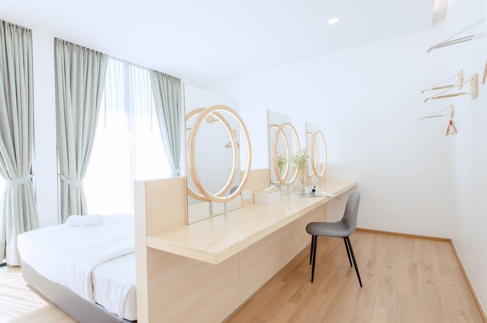Bright bedroom at Pool Lay AII Pool Villa, Na Jomtien. Features a vanity with round mirrors and a modern chair.