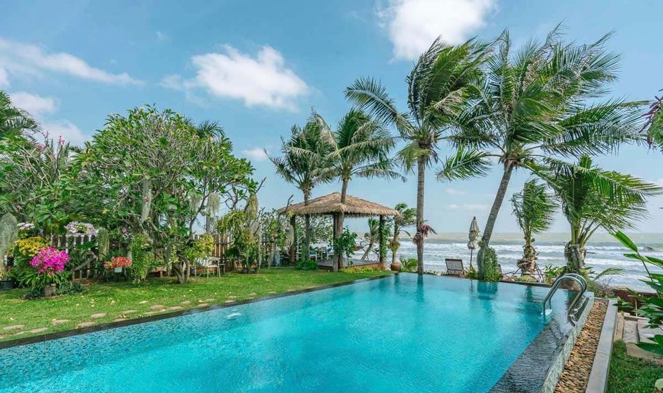 Oceanfront pool at Pran Beach Villa I, เขากะโหลก ปราณบุรี. View of the ocean and a thatched roof cabana from the pool.