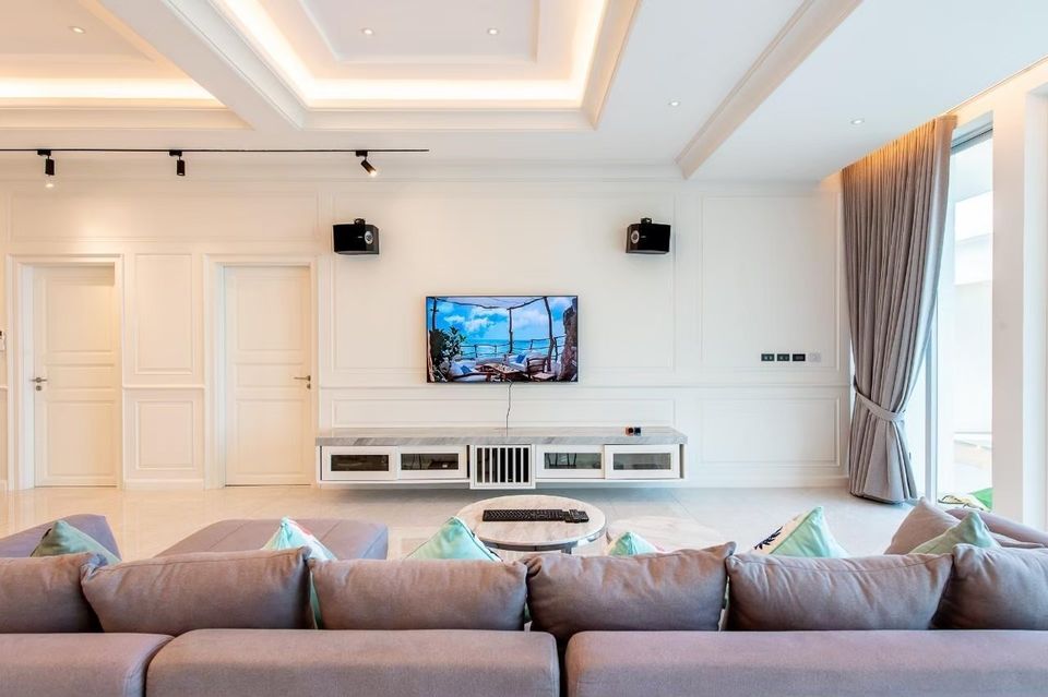 Living room at Private Heaven VI Pool Villa, Cha-Am. Features a large sofa, TV, and modern console.