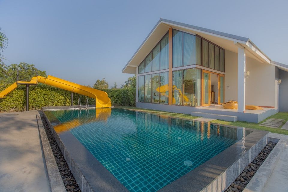 Swimming pool with waterslide at Proud II Pool Villa, Hua Hin. Modern villa with floor-to-ceiling windows.