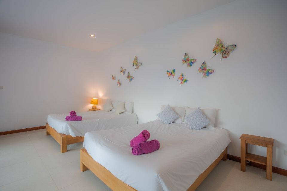 Bedroom with twin beds and butterfly wall art at Proud II Pool Villa, Hua Hin, Thailand.