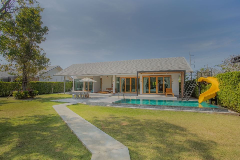Proud V Pool Villa Hua Hin features a private pool with a fun yellow water slide and outdoor dining area.