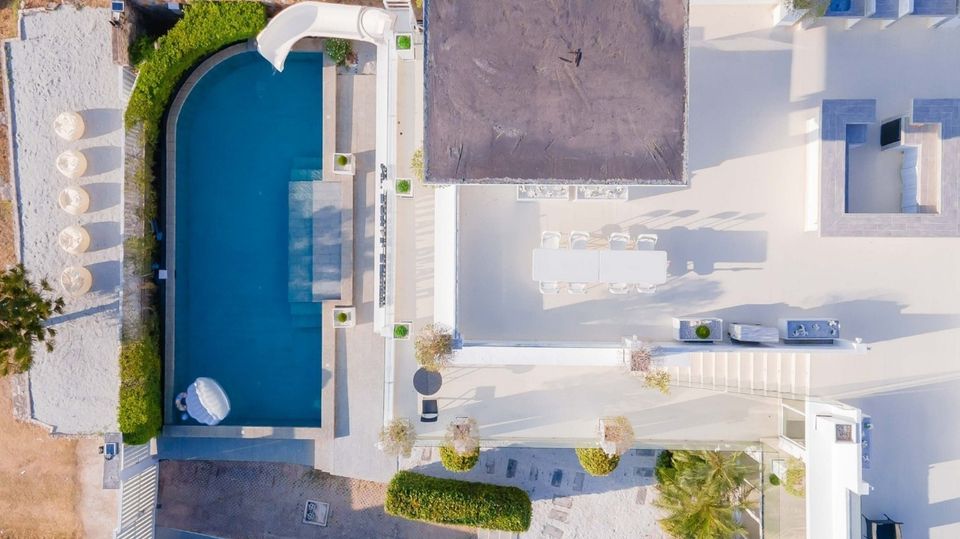 Aerial view of Royal Beach X Pool Villa, ติดทะเลนาจอมเทียน พัทยาใต้. See the pool, slide, outdoor dining, and lounge areas.