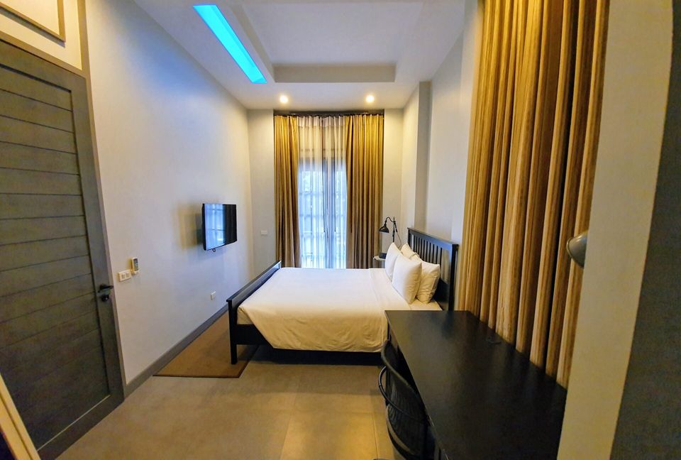 Modern bedroom with TV in Sala Haven Nine Pool Villa, South Pattaya. Comfortable bed with gold curtains.