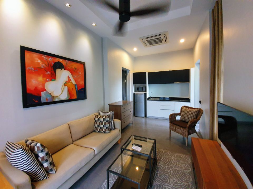 Open-plan living area with sofa and kitchenette at Sala Haven Nine Pool Villa, South Pattaya, Thailand.