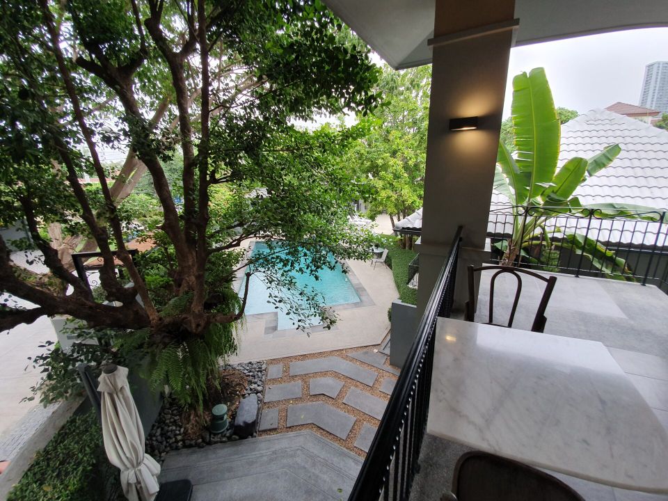 Balcony view of the pool at Sala Haven Nine Pool Villa, South Pattaya. Lush greenery surrounds the pool.