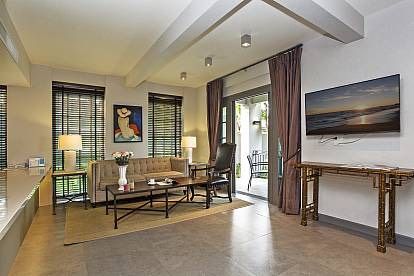 Living room with neutral decor at Sala Haven Nine Pool Villa, South Pattaya. Sofa, TV, and outdoor access visible.