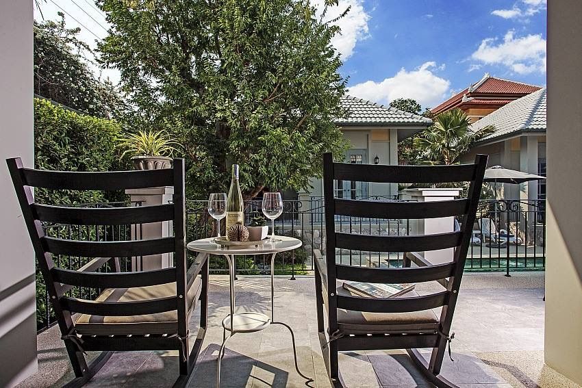 Relax on the patio at Sala Haven Nine Pool Villa, South Pattaya. Rocking chairs and wine await.
