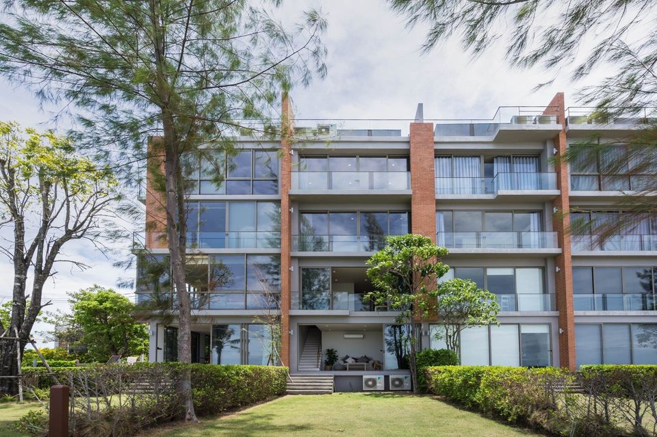 Sand Beachfront Exclusive Villa exterior view in Pattaya, Thailand. Modern building with garden and trees.
