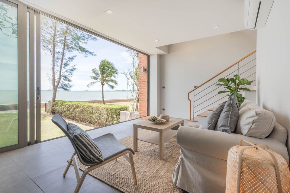Living room with ocean view at Sand Beachfront Exclusive Villa, ติดทะเลพัทยาเหนือ บางละมุง. Sofa, chair, and sliding glass do
