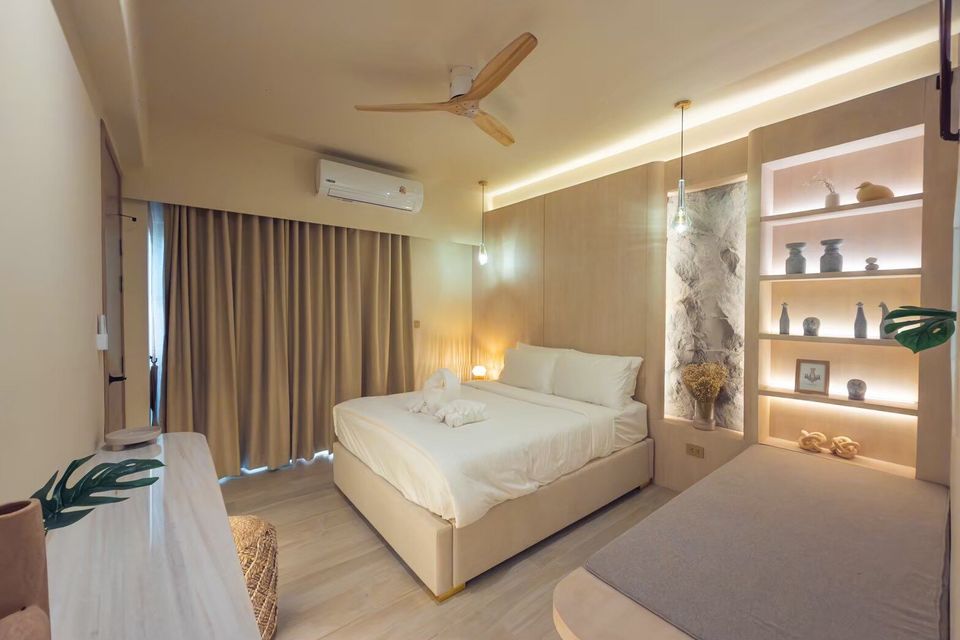 A king-size bed with white linens and decorative towels in a bedroom at Sand Moment VI Pool Villa, Rayong.