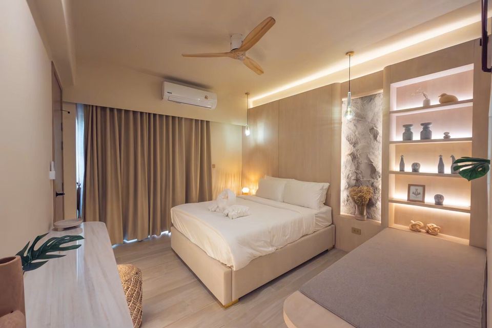 A cozy king-size bed with white linens and decorative towels in a bedroom at Sand Moment VI Pool Villa, Rayong.