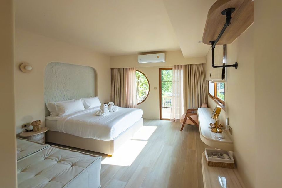 Bright bedroom at Sand Moment VI Pool Villa, Rayong, featuring a king-size bed, round window, and balcony access.