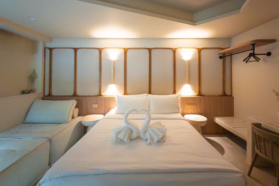 Bright bedroom at Sand Moment VI Pool Villa, Rayong, featuring a comfortable king-size bed with swan towels and a side daybed.