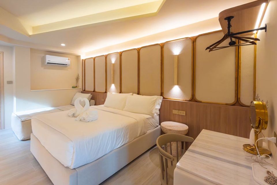 A bright bedroom at Sand Moment VI Pool Villa, Rayong, featuring a king-size bed with swan towels and elegant wall lighting.