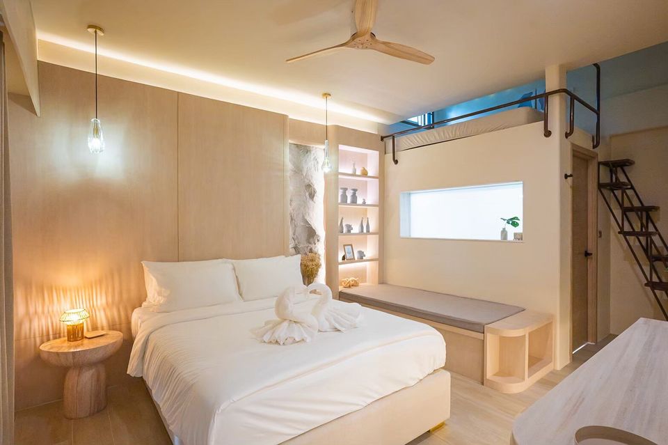 A cozy king-size bed with white linens and swan towels in Sand Moment VI Pool Villa, Rayong. Features a unique loft bed above.