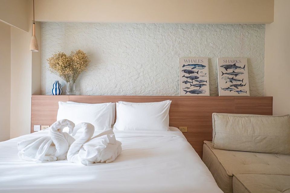 A king-size bed with white linens and swan-folded towels in a bedroom at Sand Moment VI Pool Villa, Rayong.