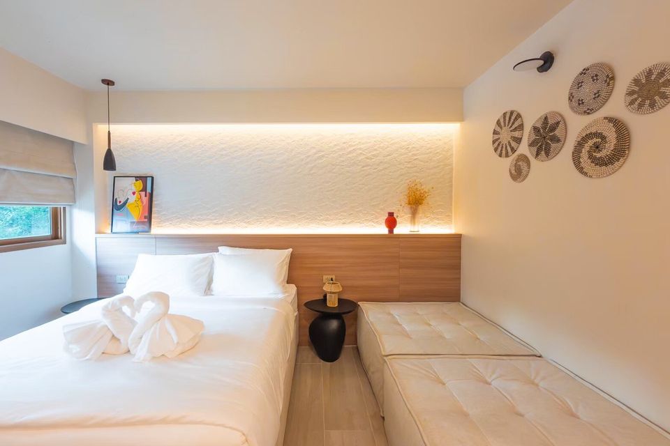 A bright bedroom at Sand Moment VI Pool Villa, Rayong, featuring a twin bed with swan towels and a comfortable daybed.