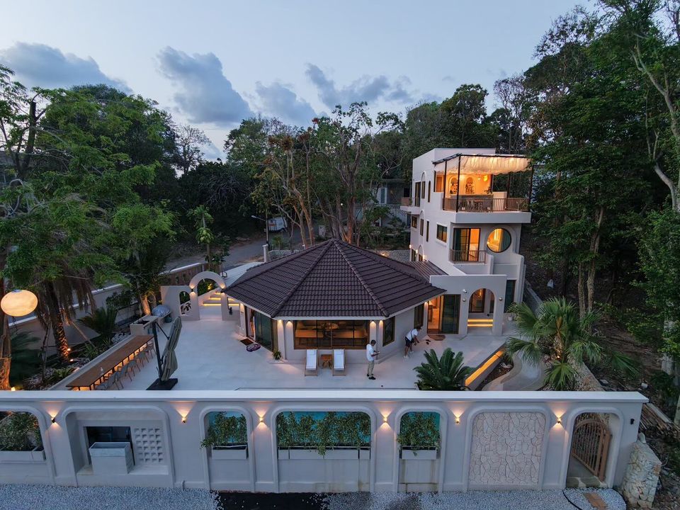 Aerial dusk view of Sand Moment VI Pool Villa in Rayong, showcasing its unique architecture and outdoor lighting.