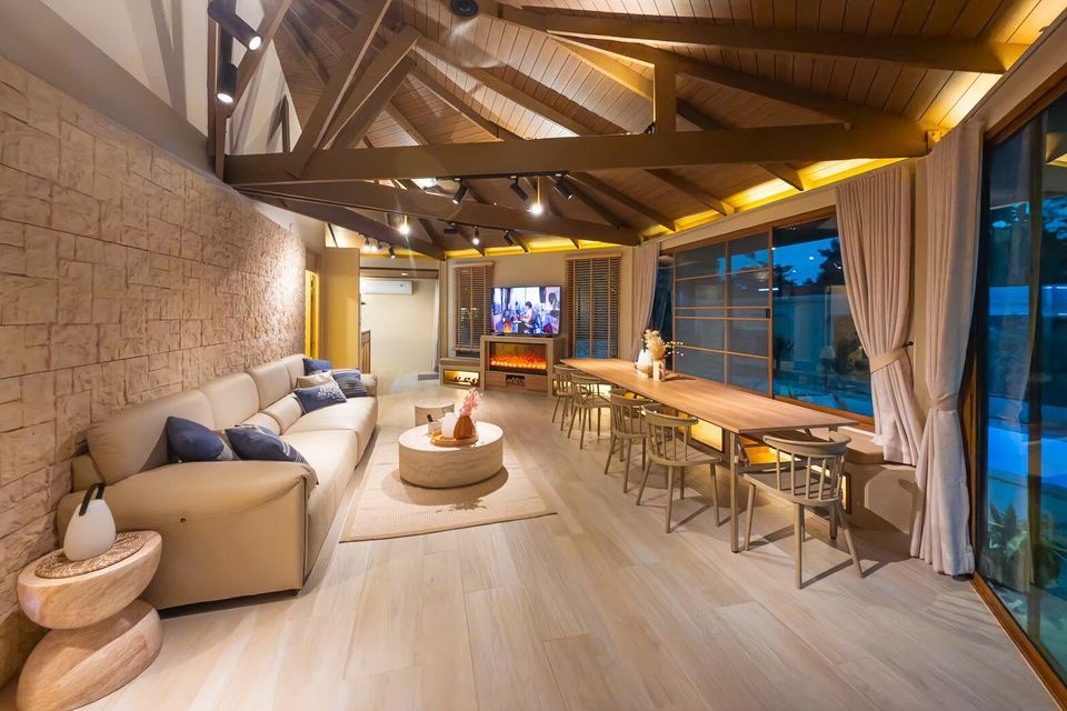 Spacious living and dining area with vaulted wooden ceiling at Sand Moment VI Pool Villa, Rayong. Features a large sofa and long dining table.