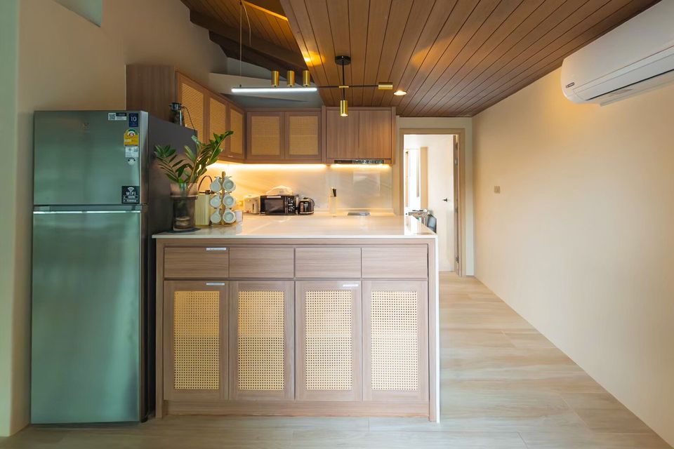 Modern kitchen with rattan cabinets, stainless steel fridge, and wooden ceiling at Sand Moment VI Pool Villa, Rayong.