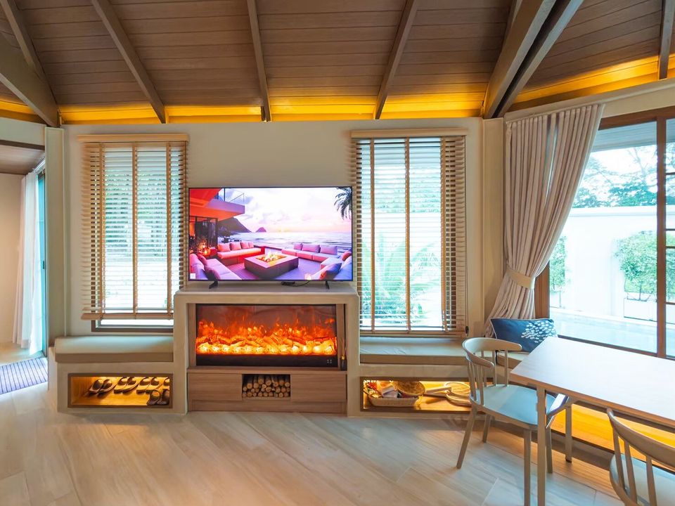 Modern living area with large TV, electric fireplace, and dining table at Sand Moment VI Pool Villa, Rayong.