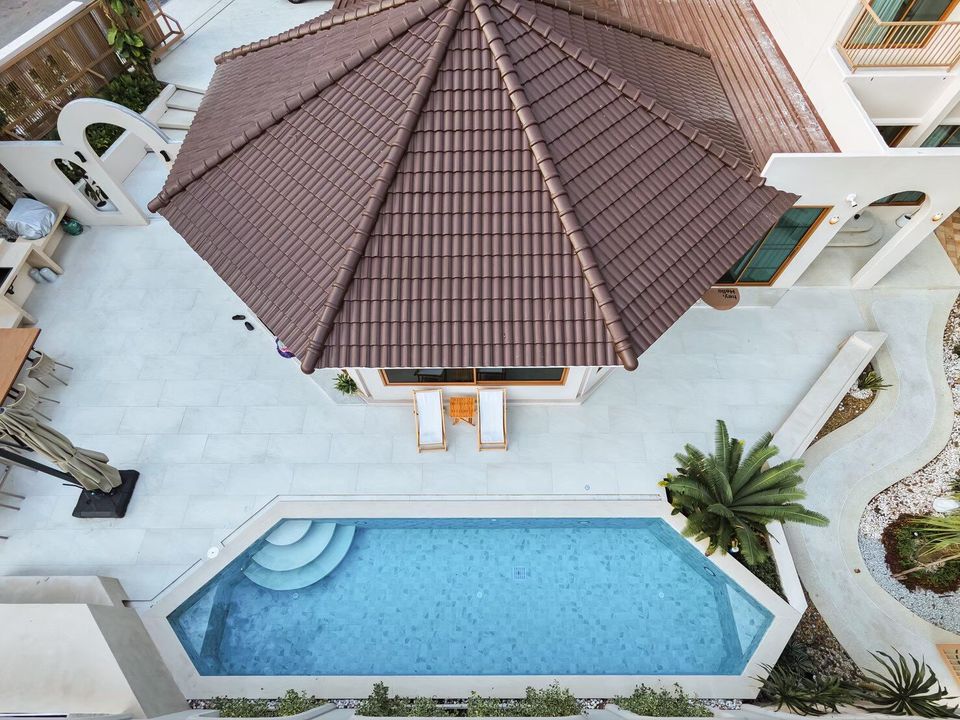 Aerial view of Sand Moment VI Pool Villa in Rayong, showing the unique pool shape, brown roof, and white exterior.