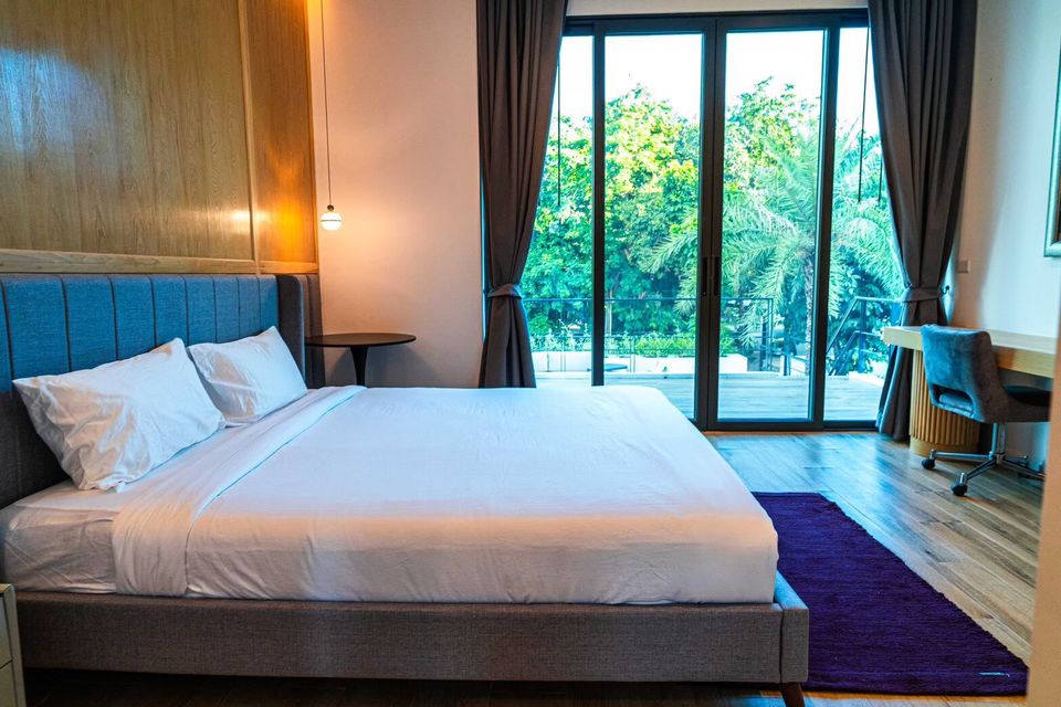 Spacious bedroom at Sea Moment IV Pool Villa, Rayong, featuring a comfortable king-size bed and a private balcony with lush views.