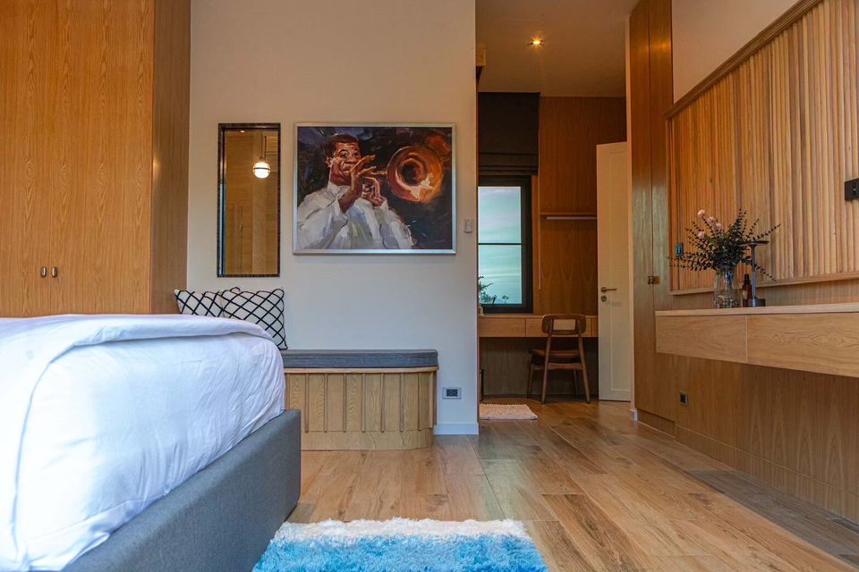 Modern bedroom with wood paneling, a comfortable bed, and unique trumpet player art at Sea Moment IV Pool Villa, Rayong.