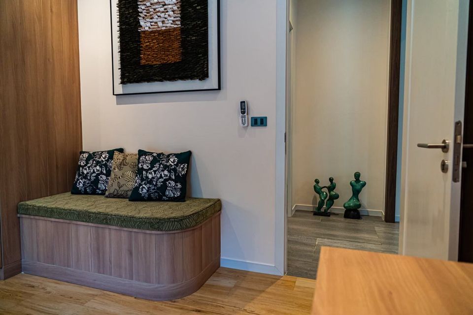 A cozy hallway seating nook with decorative pillows and unique green sculptures at Sea Moment IV Pool Villa, Rayong.
