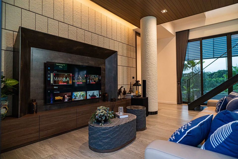 Modern living room with large TV, comfortable sofa, and stylish coffee tables at Sea Moment IV Pool Villa, Rayong.
