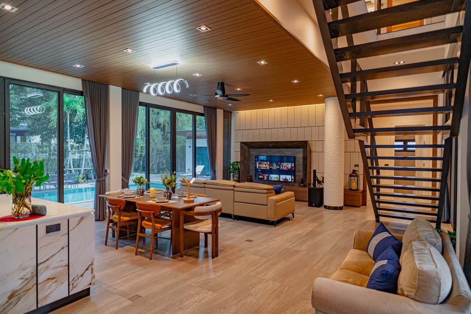 Spacious open-plan living and dining area at Sea Moment IV Pool Villa, Rayong, with pool views and modern decor.