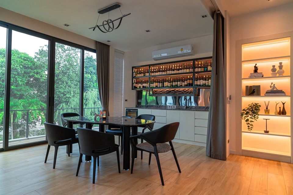 Modern dining area with a black table, chairs, and a built-in wine bar at Sea Moment IV Pool Villa, Rayong.