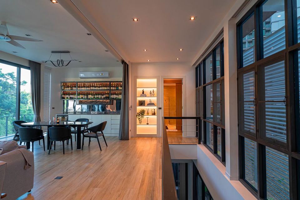 Interior view of Sea Moment IV Pool Villa, Rayong, showing a stylish wine bar, dining area, and illuminated hallway.