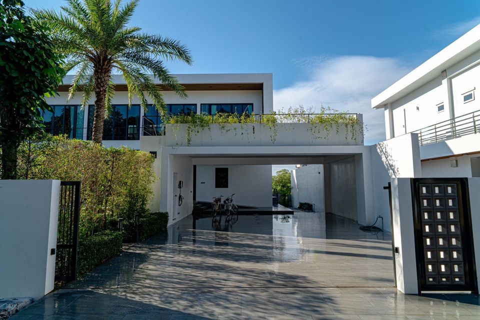 Modern entrance and carport of Sea Moment IV Pool Villa in Rayong, featuring sleek architecture and lush greenery.